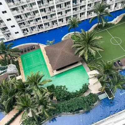 an overhead view of a large swimming pool with palm trees at Crizzy's Hub Crizel at Shore Residences - 1BR with Balcony and Amenity view - Netflix and Disney - Near MOA in Manila