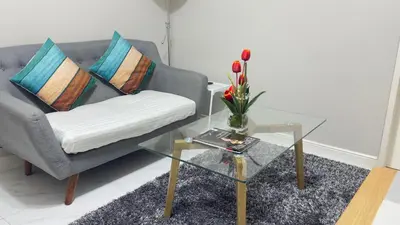 a living room with a couch and a glass table at Monarch Parksuites Balmoral Place Unit 1616 in Manila