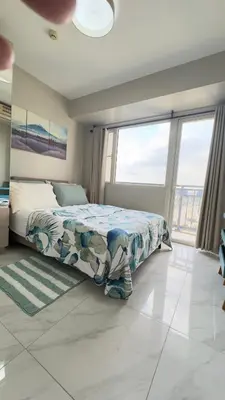 a bedroom with a bed and a large window at Monarch Parksuites Balmoral Place Unit 1616 in Manila