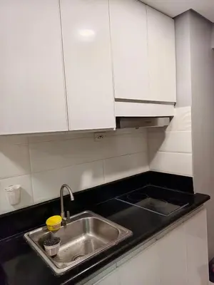 a kitchen counter with a sink and white cabinets at Experience Unforgettable Moments in Manila