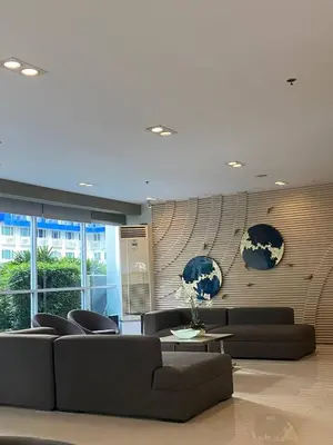 a living room with two couches and a table and a wall at Sea Residence By Kenshin Staycation in Manila