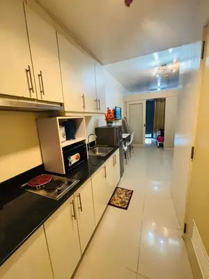 a kitchen with white cabinets and black counter tops at Sea Residence By Kenshin Staycation in Manila