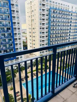 a balcony with a view of buildings and a pool at Sea Residence By Kenshin Staycation in Manila