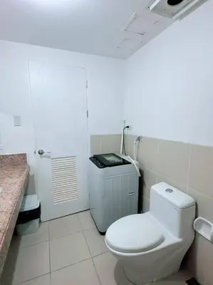 a white bathroom with a toilet and a sink at Tan condo fairway in Manila