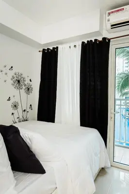 a white bed with black curtains and a window at Premium family Suite near MOA in Manila