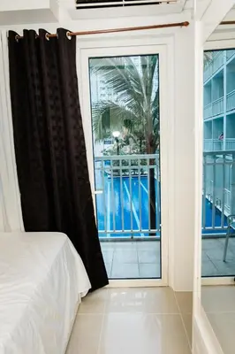 a bedroom with a window with a view of a balcony at Premium family Suite near MOA in Manila