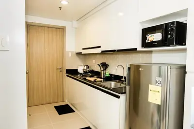 a kitchen with a stainless steel refrigerator and a sink at Premium family Suite near MOA in Manila