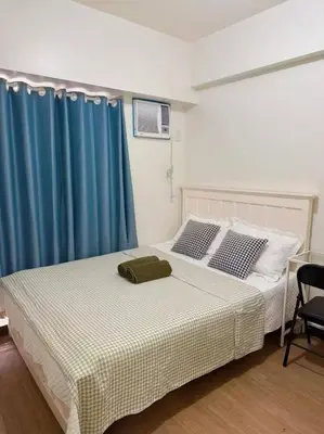 a bedroom with a bed and a blue curtain at Tan condo city view 01 in Manila