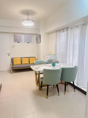a living room with a table and chairs and a couch at Tan condo city view 01 in Manila