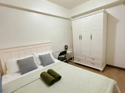 a bedroom with a large white bed with two green pillows at Tan condo city view 01 in Manila