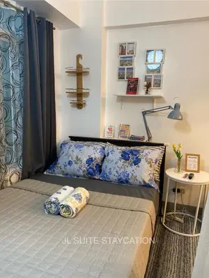 a bedroom with a bed with blue and white pillows at JL Suite Staycation near Venice Grand Canal Mall in Manila