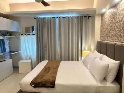 a bedroom with a large bed and a window at JL Suite Staycation near Venice Grand Canal Mall in Manila
