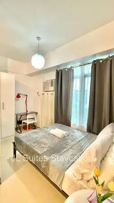 a bedroom with a large bed with a window at JL Suite Staycation near Venice Grand Canal Mall in Manila