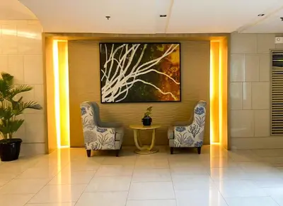 two chairs and a table in a lobby with a painting at Unistay SHELL Residence Amazing pool near MOA in Manila
