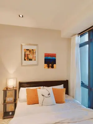 a bedroom with a bed with orange and white pillows at Gramercy Residences Cozy 1BR Suite with 600mbps & Free amenities City view in Manila