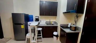 a small kitchen with a refrigerator and a sink at 21K Pioneer Woodlands Mandaluyong in Manila