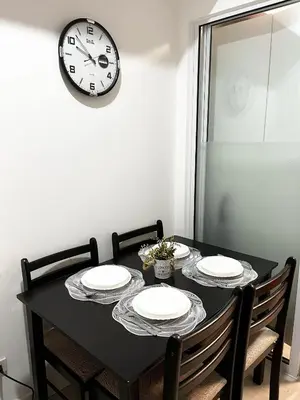 a black table with four chairs and a clock on the wall at Azure Staycation by Casa Lepap in Manila