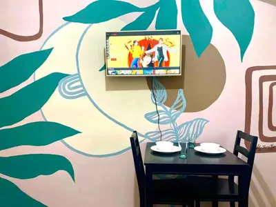 a dining room with a table and a tv on a wall at Studio in the Metro I Near MRT I WiFi in Manila