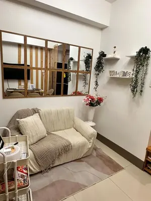 a living room with a couch and a mirror at Cozy 1 BR in EDSA Mandaluyong in Manila