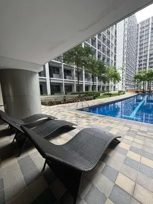 a swimming pool in a building with black chairs at Shore 2 Residences Tower 1 in Manila