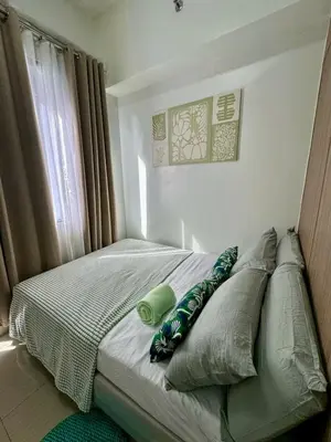 a bedroom with a bed with pillows and a window at Staycation bliss! Shore 2 B1! in Manila