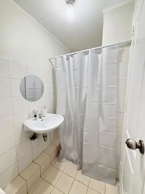 a bathroom with a white shower curtain and a sink at Cozy 2BR Condo Free Pool Access in Manila