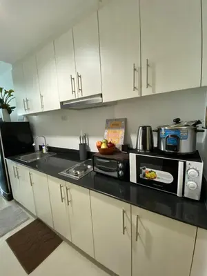 a kitchen with white cabinets and a microwave at Sea Crib in Manila