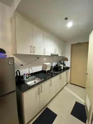 a kitchen with white cabinets and a sink and a refrigerator at Sea Crib in Manila