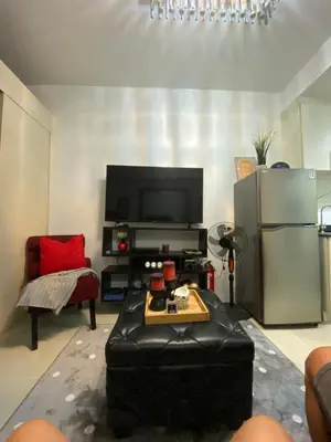 a living room with a black leather couch and a television at Sea Crib in Manila
