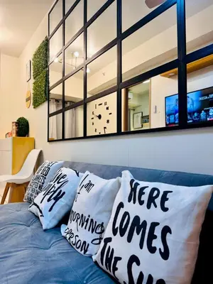 a living room with a blue couch with pillows at hearth of ember 3 Shore 3 Res in Manila
