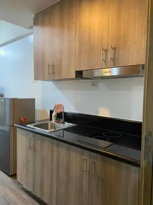 a kitchen with wooden cabinets and a sink at FX Condotel 3322 in Manila