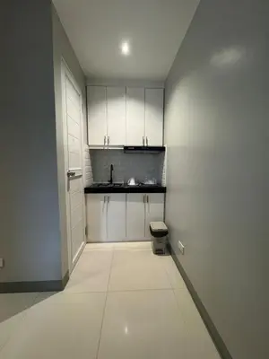 a small kitchen with white cabinets and a toilet at Santipha Residences in Manila