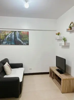 a living room with a couch and a flat screen tv at Alea Residence 21 in Manila