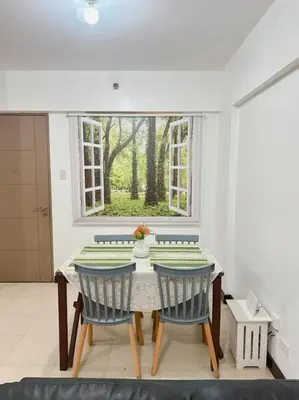 a dining room with a table and chairs and a window at Alea Residence 21 in Manila