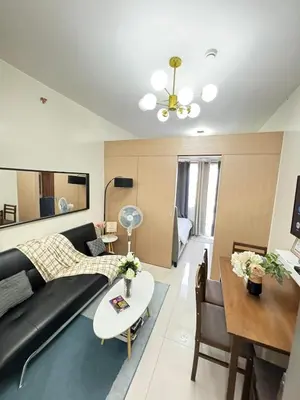 a living room with a black couch and a table at Staycation at Field Residences Near Airport in Manila