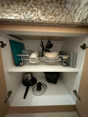 a shelf with dishes and utensils in a kitchen at Staycation at Field Residences Near Airport in Manila