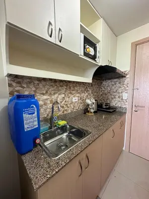 a kitchen with a sink and a blue trash can at Staycation at Field Residences Near Airport in Manila