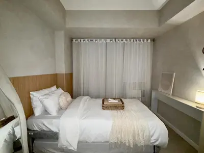 a small bedroom with a white bed and a window at 2BR - Azure Staycation Parañaque in Manila