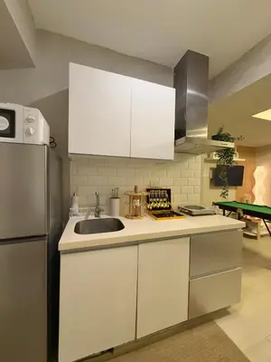 a kitchen with white cabinets and a sink and a refrigerator at 2BR - Azure Staycation Parañaque in Manila