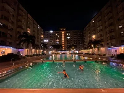 two people swimming in a swimming pool at night at 2BR Condo Staycation NearAirport in Manila