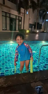 a young boy is standing in a swimming pool at Charles Haven's Crib - Spring Residences in Manila
