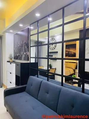 a living room with a blue couch and a large window at Shore 3 - 1BR Scandi-Industrial Condo Suite by The Bay in Manila