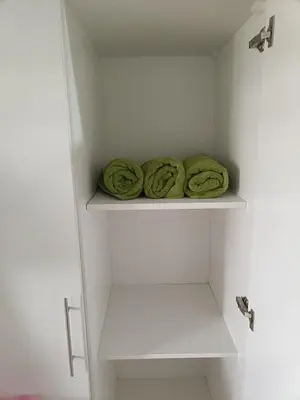 a white closet with green towels on a shelf at Lyleis' Getaway in Manila