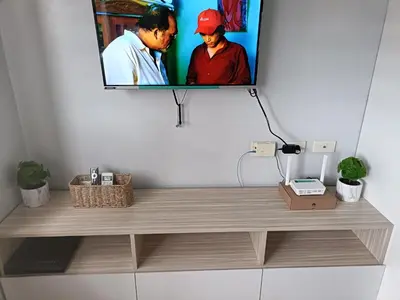 a tv hanging on a wall with a wooden shelf at Lyleis' Getaway in Manila