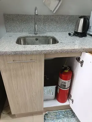 a kitchen sink with a fire extinguisher under a counter at Lyleis' Getaway in Manila