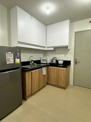 a kitchen with white cabinets and a black refrigerator at 2 bedroom unit near BGC Taguig and NAIA Airport in Manila