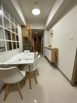 a dining room with a white table and chairs at Happy Sunshine Staycation Moa near Airport in Manila