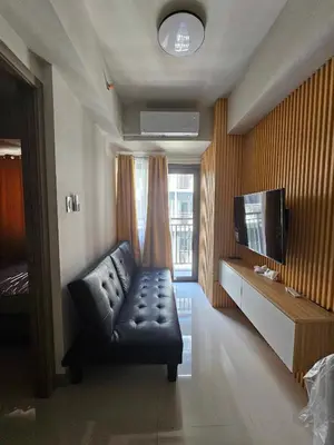 a living room with a couch and a flat screen tv at Happy Sunshine Staycation Moa near Airport in Manila