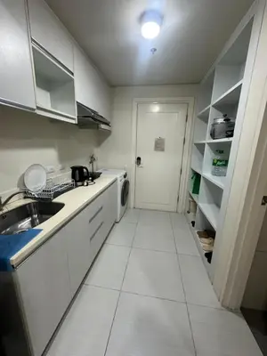 a kitchen with white cabinets and a sink and a door at Lugar Kalinaw in Manila