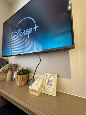 a television on a wall above a table with books at Einjel's Hideaway in Manila